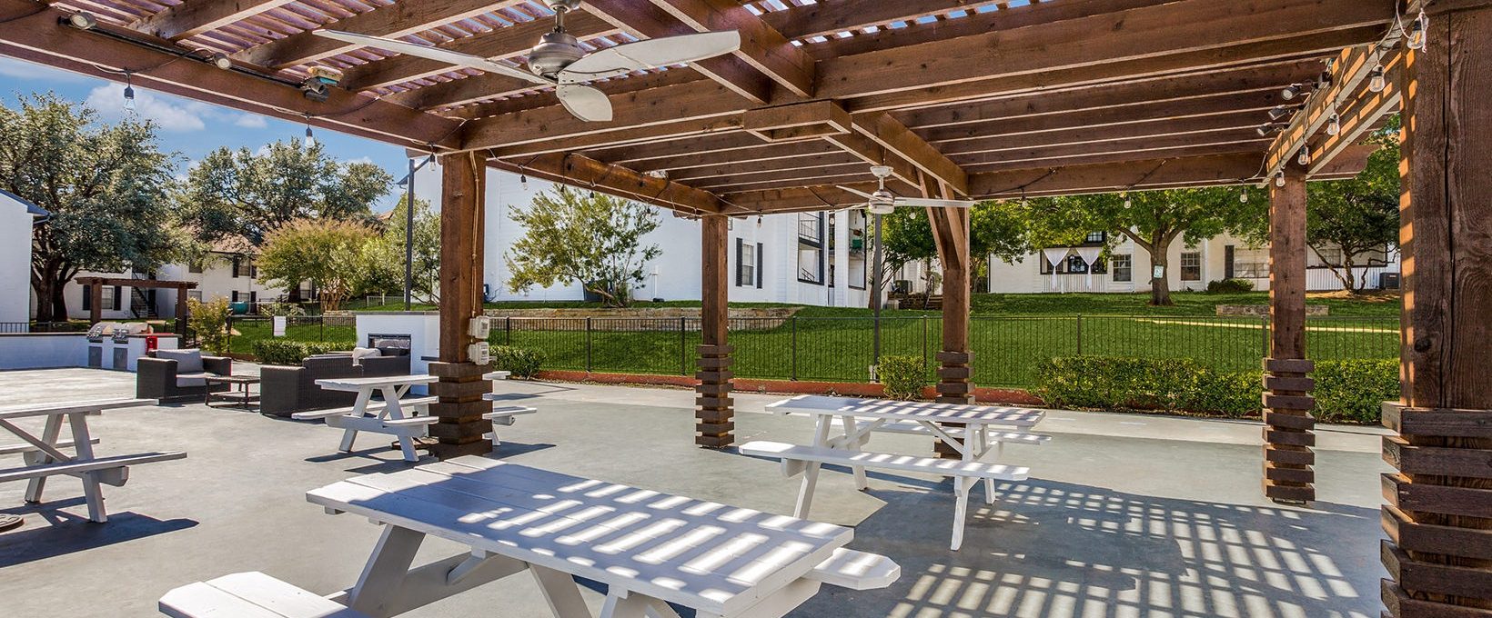 Covered outdoor picnic area with picnic tables and fans over the tables