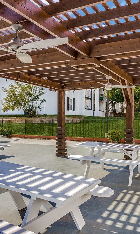 Covered outdoor picnic area with picnic tables and fans over the tables